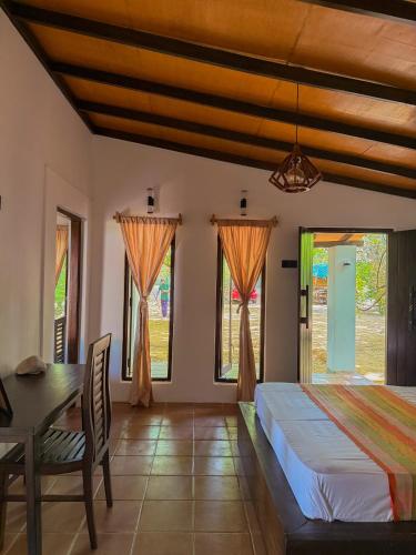 une chambre avec un lit, une table et des fenêtres dans l'établissement In the Wild by RoamCeylon, à Polonnâruvâ