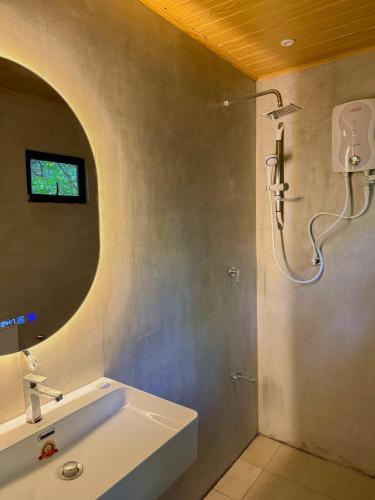 La salle de bains est pourvue d'une douche et d'un lavabo blanc. dans l'établissement In the Wild by RoamCeylon, à Polonnâruvâ