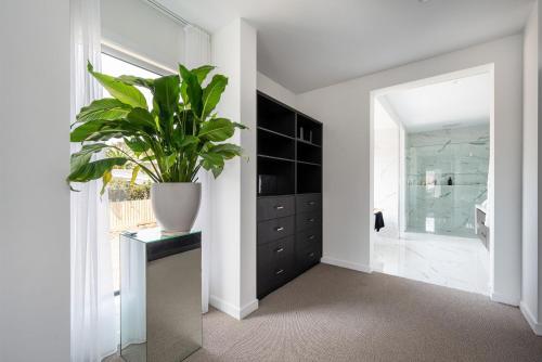a bathroom with a plant in a vase on a cabinet at Villa Capri - Luxe Modern by the Village in Mount Eliza