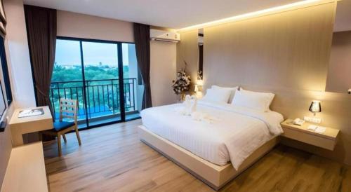 a bedroom with a large white bed and a balcony at L Hotel in Ban Si Than