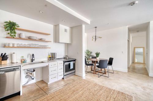 a kitchen with white cabinets and a table with chairs at Studio Bliss Dual-Queen Stay in Vibrant Alberta in Portland