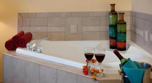 a bath tub with two glasses of wine and wine bottles at Magnuson Grand Conference Hotel in Cypress Gardens