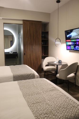 a hotel room with two beds and a flat screen tv at OTMÁNN Hotel Boutique in Guadalajara