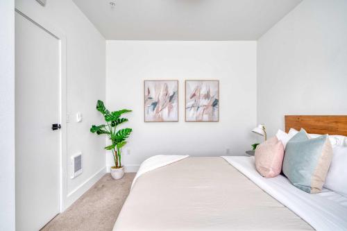 a white bedroom with a bed with a plant at Stay Portland - Stylish Luxe Suite N Williams & Alberta Districts in Portland