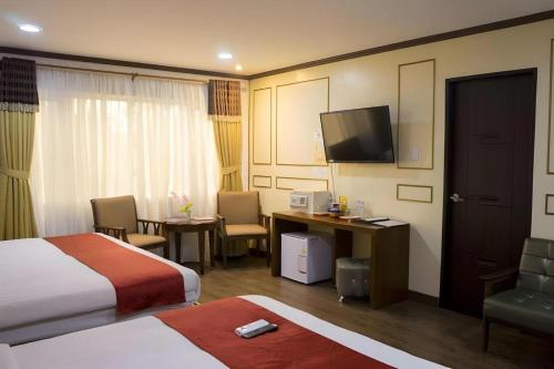 a hotel room with a bed and a desk and a television at Horizon Hotel in Olongapo