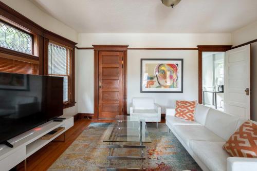ein Wohnzimmer mit einem weißen Sofa und einem Flachbildfernseher in der Unterkunft Stay Portland - Historic PDX Home - Sleeps 10, Perfect Location in Portland