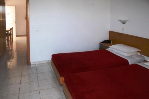 a bedroom with two beds and a red blanket at Barbie Hotel Apartments in Ialyssos