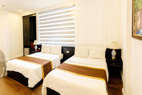 two beds in a room with a window at Royal Hotel Hà Nội in Hanoi