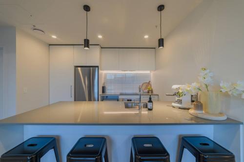 Una cocina con una encimera con fregadero y cuatro taburetes. en Cityside Comfort Modern 2BR 2BA with Parking, en Christchurch