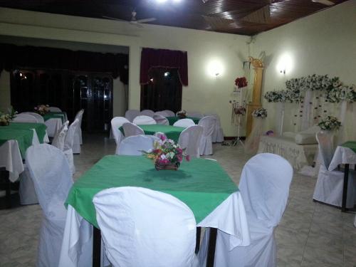 a banquet room with green tables and white chairs at Hansika Guest Inn in Buttala