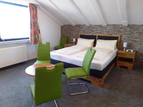 a bedroom with a bed with green chairs and a table at Hotel Brandl in Bad Wörishofen