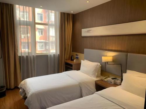 a hotel room with two beds and a window at JTOUR Inn Huangshi North Station Cihu Scenic Area in Huangshigang