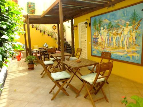 a patio with wooden tables and chairs and a painting at Kira's Boutique Hotel in Mindelo