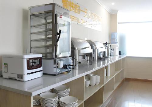 a kitchen with a counter with plates and a coffee maker at City Comfort Inn Huizhou Zhongkai Huihuan in Huizhou