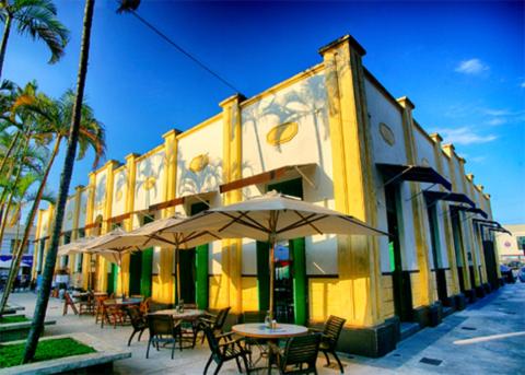 a yellow building with tables and chairs and an umbrella at Loft aconchegante in Ilhota