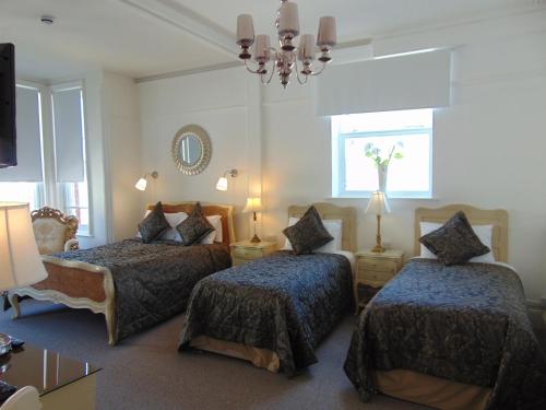 a bedroom with two beds and a chandelier at Holywell House in Loughborough