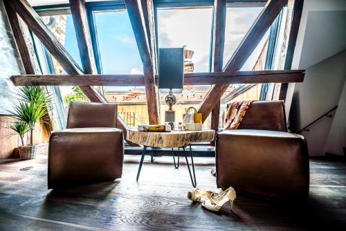 ein Zimmer mit 2 Stühlen und einem Tisch vor einem großen Fenster in der Unterkunft PEST-BUDA Design Hotel in Budapest