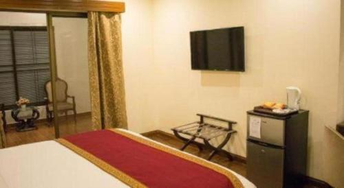 a hotel room with a bed and a flat screen tv at Hotel Grand Millennium in Lahore