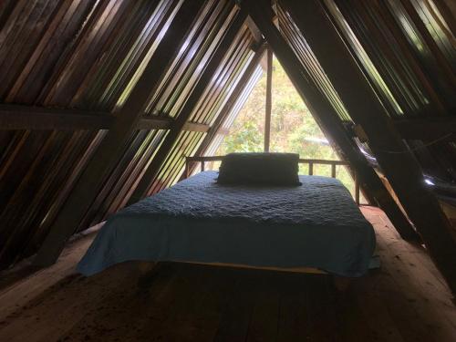 een bed in een houten kamer met een raam bij Finca MamaChakra - Cabañas - Camping in Cumandá