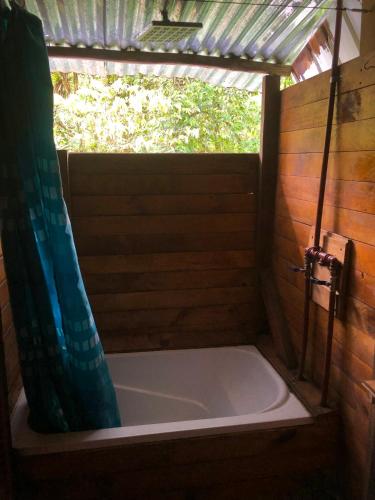 a bathroom with a tub with a shower curtain at Finca MamaChakra - Cabañas - Camping in Cumandá