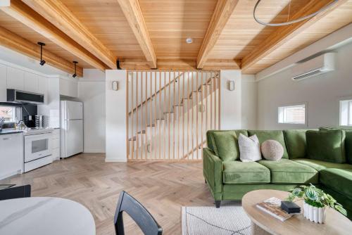 a living room with a green couch and a kitchen at Stay Portland - Alberta Arts Escape - Modern 3BR Townhome in Portland