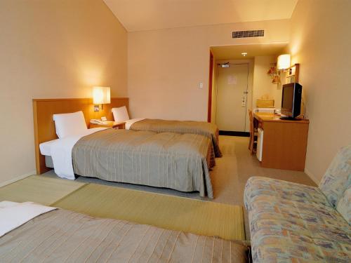 a hotel room with two beds and a television at Hotel Folkloro Hanamakitowa in Hanamaki
