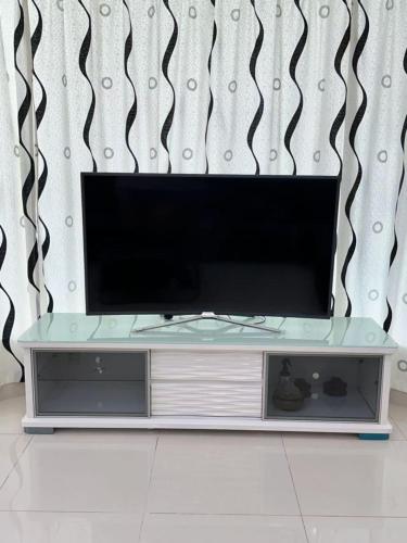 een flatscreen-tv zittend op een entertainment center bij 家家民宿 in Nibung Tebal