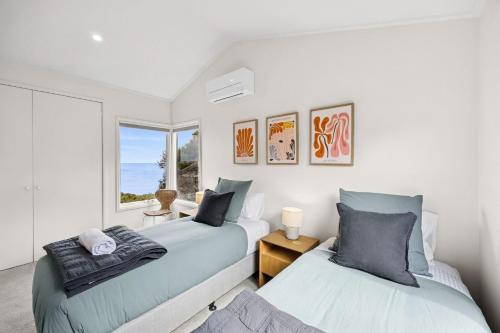 two beds in a room with a window at Heath Cliff House in Aireys Inlet