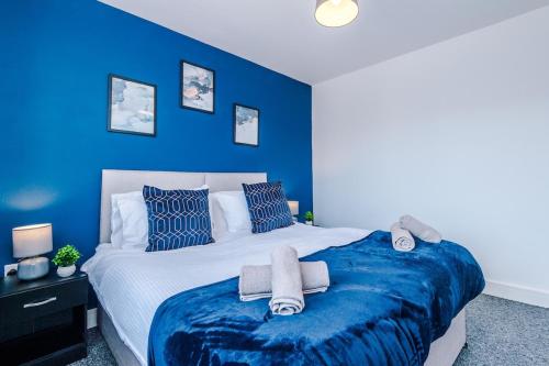 a blue bedroom with a large bed with towels on it at 4 BDR House By Eason Stays Short Lets & Serviced Accommodation St Helens With Free Parking in Saint Helens