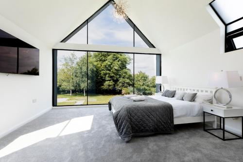 a bedroom with a bed and a large window at 6 BR Luxury House With Huge Garden and Cinema Room By Eason Stays Short Term Rental Rugby in Long Lawford