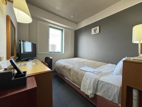 a hotel room with a bed and a desk with a computer at Ace Inn Matsusaka in Matsuzaka