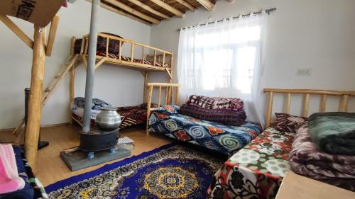 a room with a bunk bed and a couch and a fireplace at Serenity Stay Rangrik in Kaza