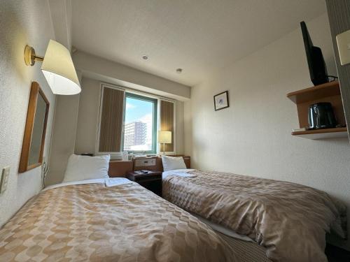 Una habitación de hotel con dos camas y una ventana. en Ace Inn Matsusaka, en Matsusaka