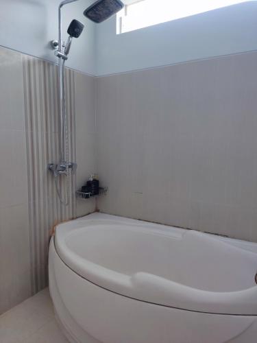 eine weiße Badewanne in einem Badezimmer mit Licht in der Unterkunft Tropical Homestay of Balirejo in Demangan