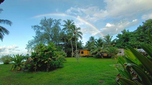 a rainbow in the sky over a yard with a house at Moana at Teahupo'o in Teahupoo