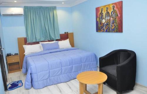 a bedroom with a bed and a chair and a table at PnK Inn in Adeleye