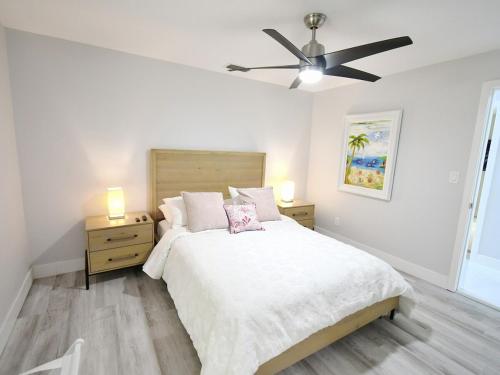 a white bedroom with a bed and a ceiling fan at Waterfront l Private Pool l Dock l Sunset Views in St Petersburg