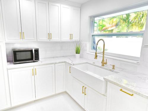 a white kitchen with a sink and a microwave at Waterfront l Private Pool l Dock l Sunset Views in St Petersburg