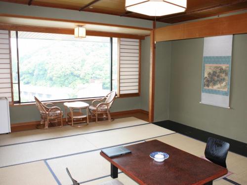 a room with a table and chairs and a window at Yamamura Bekkan in Nagato