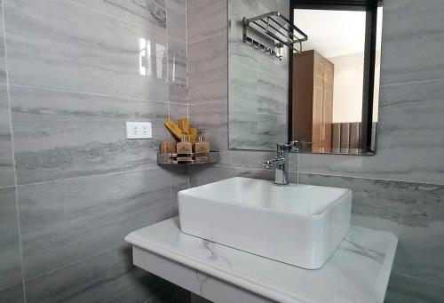 a bathroom with a white sink and a mirror at Khách Sạn Á Châu in Trại Khao