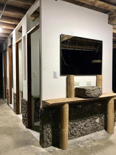 a tv on a wall with a stone bench at Hostal Tierra de Nubes in Melgar