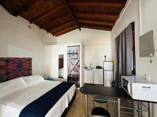 een slaapkamer met een bed en een bureau met een televisie bij Aloja-T en Apartaloft amoblado en Jericó in Jericó