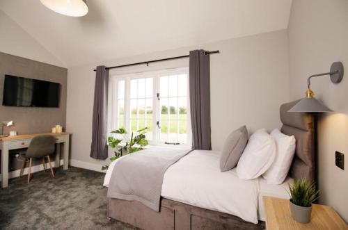 a bedroom with a bed and a desk and a window at The Kings Arms in Coggeshall