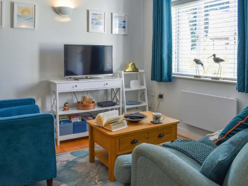 a living room with a couch and a tv at Kingfisher Cottage, 20 in Camelford