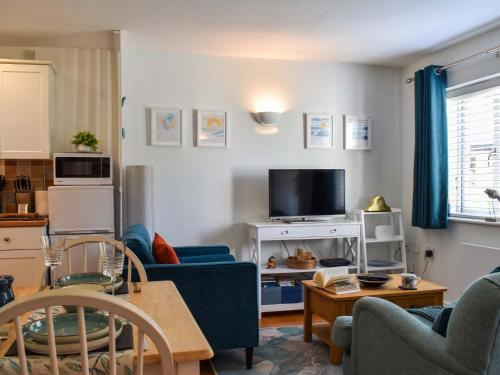 a living room with blue chairs and a tv at Kingfisher Cottage, 20 in Camelford