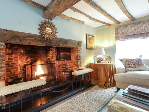 a living room with a brick fireplace and a couch at Lynchets Cottage in Lambourn