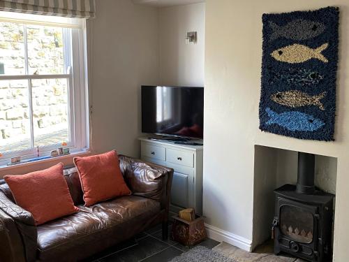 a living room with a leather couch and a flat screen tv at Holme Crest in Staithes
