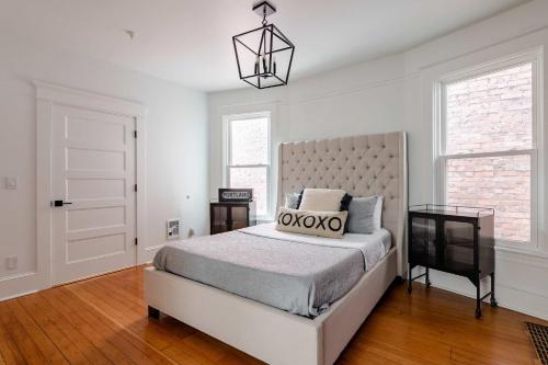 a white bedroom with a bed and a chandelier at Stay Portland - Sophisticated 2BR - Prime NW 23rd Location in Portland