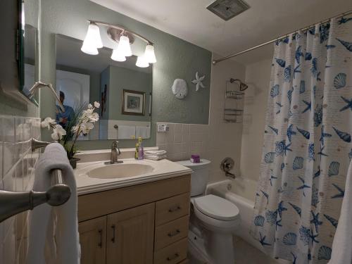 Un baño con lavabo, inodoro y cortina de ducha. en Beachfront Condo, Ocean Views, Near Patrick SFB, en Satellite Beach