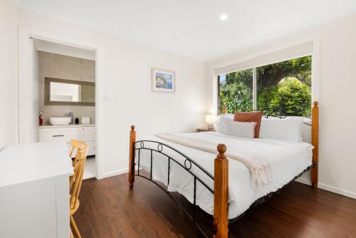 a white bedroom with a bed and a window at Olive Grove - Pet Friendly with Fireplace in Bellawongarah
